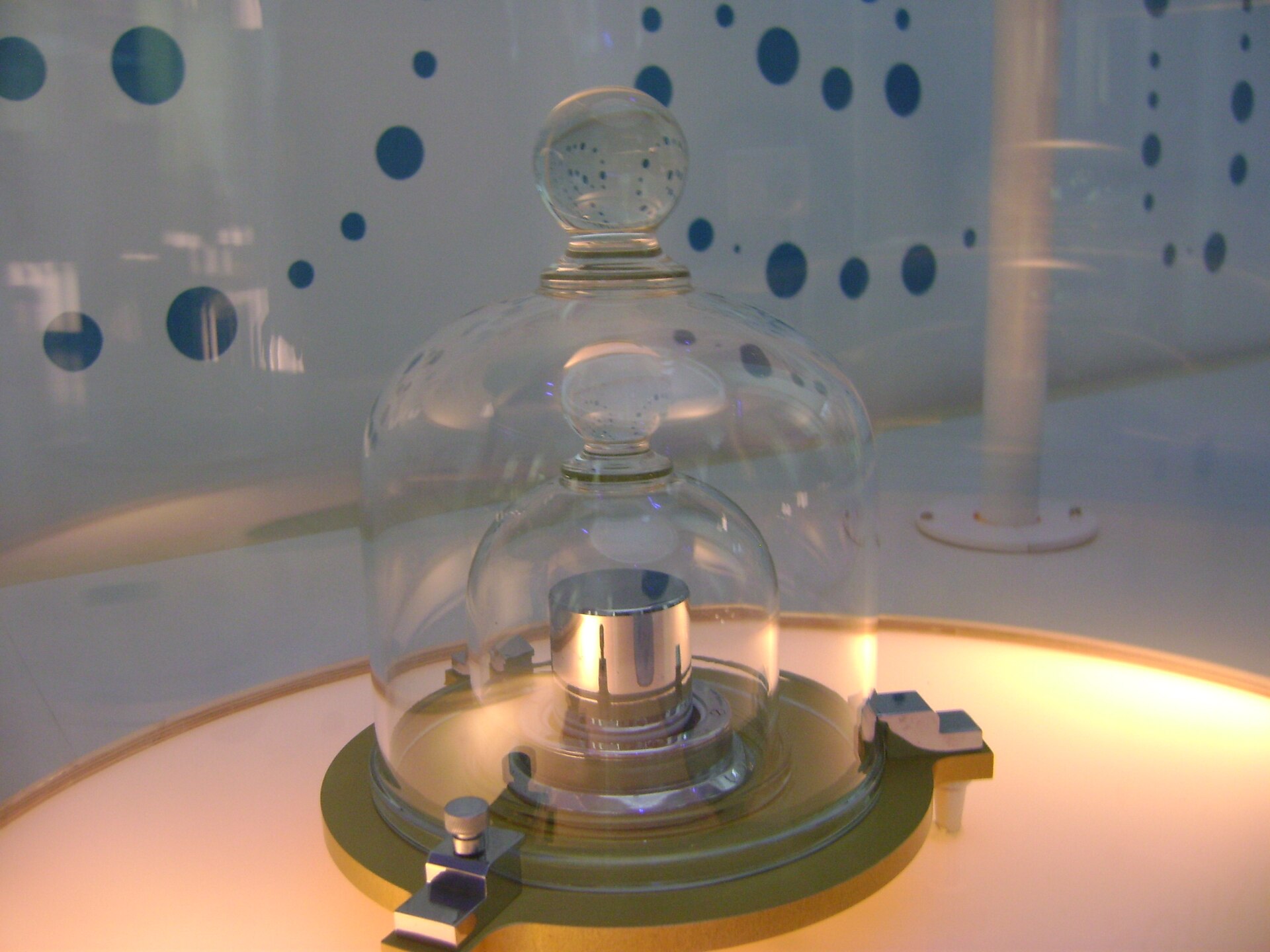 A polished metal cylinder standing under a pair of glass bell jars